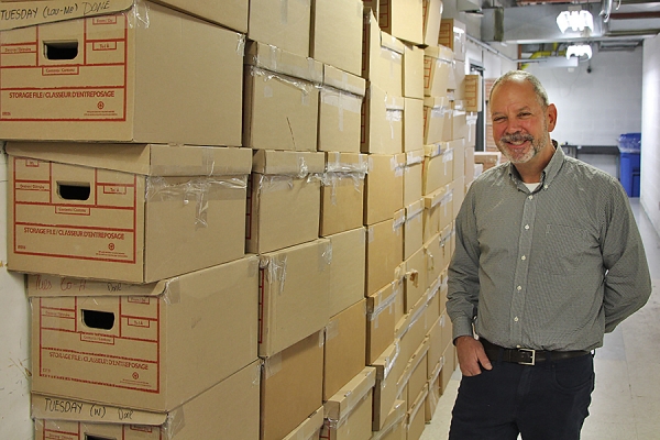 pharmacist standing next to tall stack of boxes