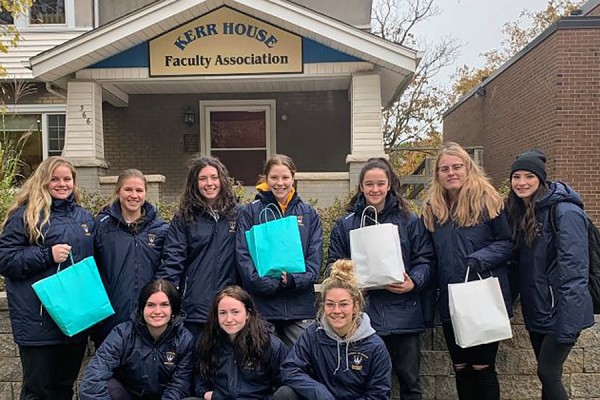Members of the Lancer women’s hockey team hold bags of donated goods