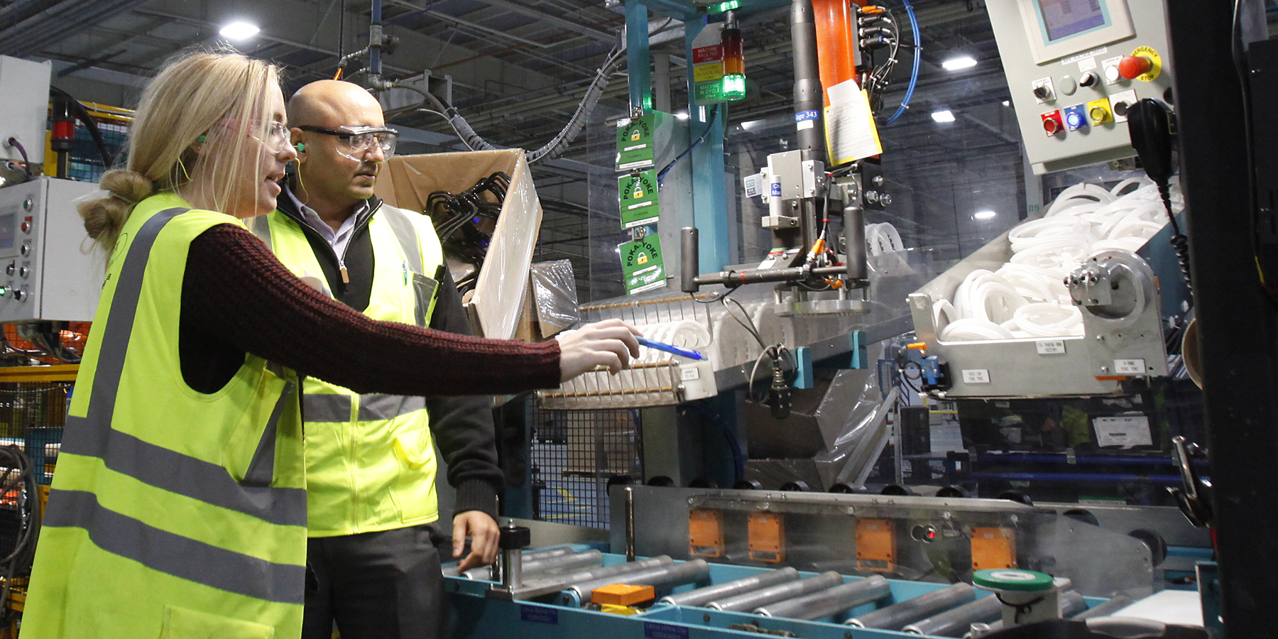 Engineers wearing a vest and goggles working with an equipment.