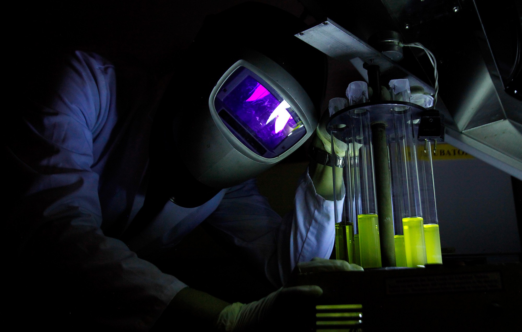 Person covering face with the help of helmet and working with chemicals with the help of equipment.