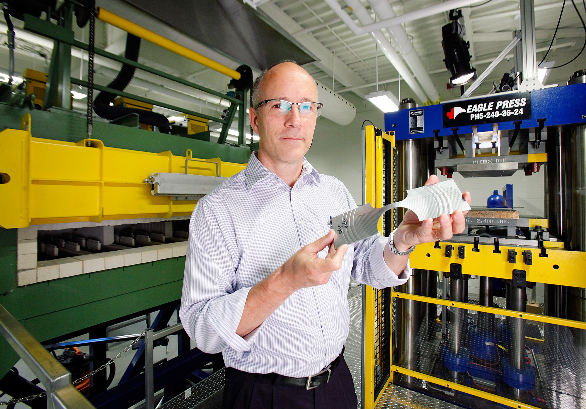 Dr. Daniel Green displays a sheet metal specimen in the Mechanical Testing Lab at the Ed Lumley Centre for Engineering Innovation. The specimen was stretch-formed in a formability test. 