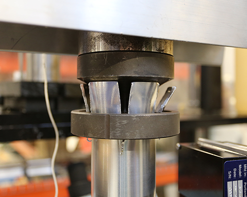 Closeup view of patented, cutting-based kinetic energy dissipation system installed on a drop tower impact testing machine