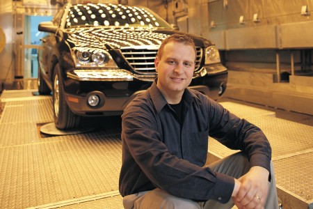 Egidio Mosca, a UWindsor alumnus, poses in front of a vehicle..
