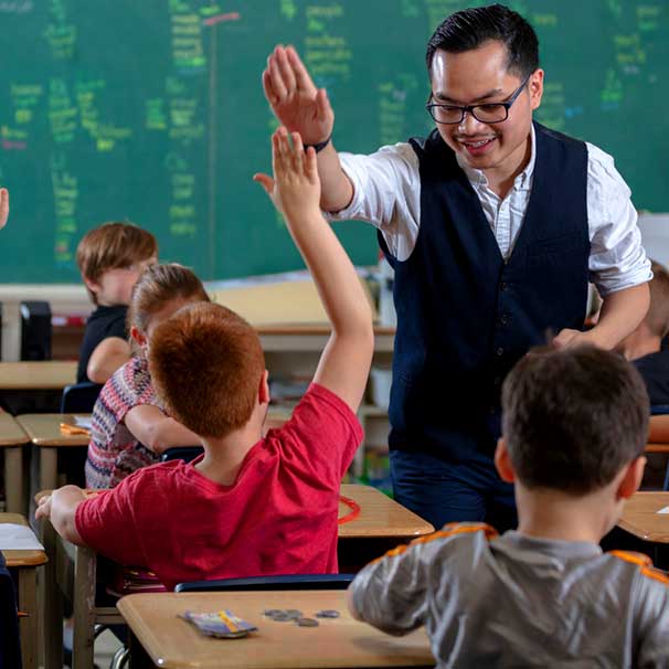 Asian male teacher high-fiving a student in class