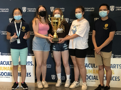 A picture of students and the Student Experience Coordinator holding a gold trophy