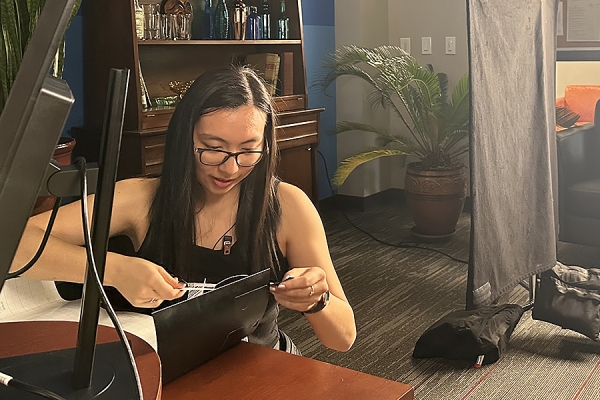 Film student Ashley Jun applies labels to cover prop computer logos on the set of “Show and Tell,” a professional production shooting in Windsor last month.