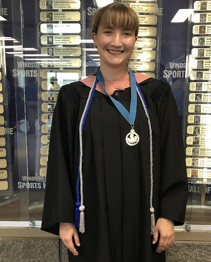 Photo of Emma Chenier taken just after Convocation Emma is wearing robe, Music hood, LEAD Scholars gold medal and "with distinction" cord
