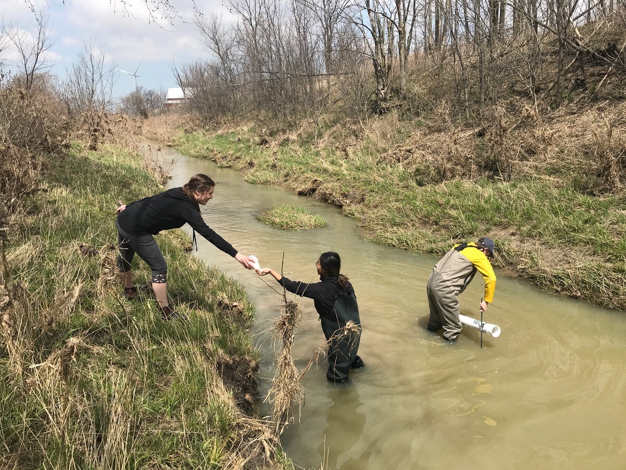 people collecting water samples from a stream