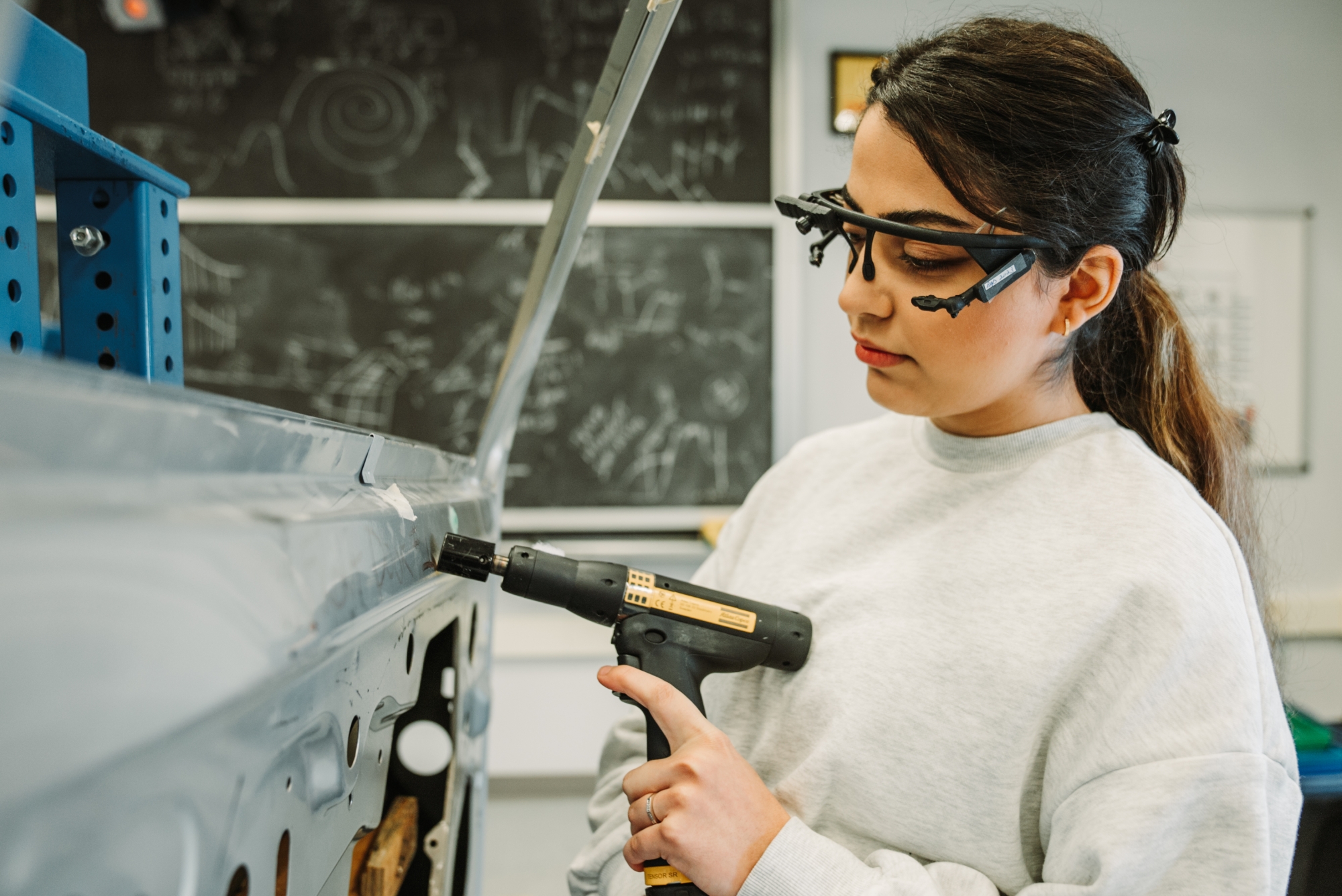 A student researcher drilling metal