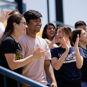 Students smiling and cheering at a football game