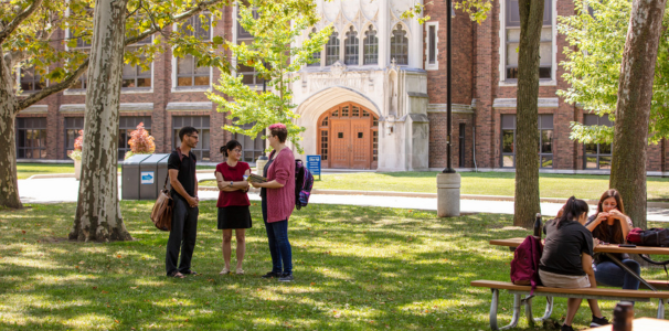 gorup of peple standign in front of a dillon hall in summer 