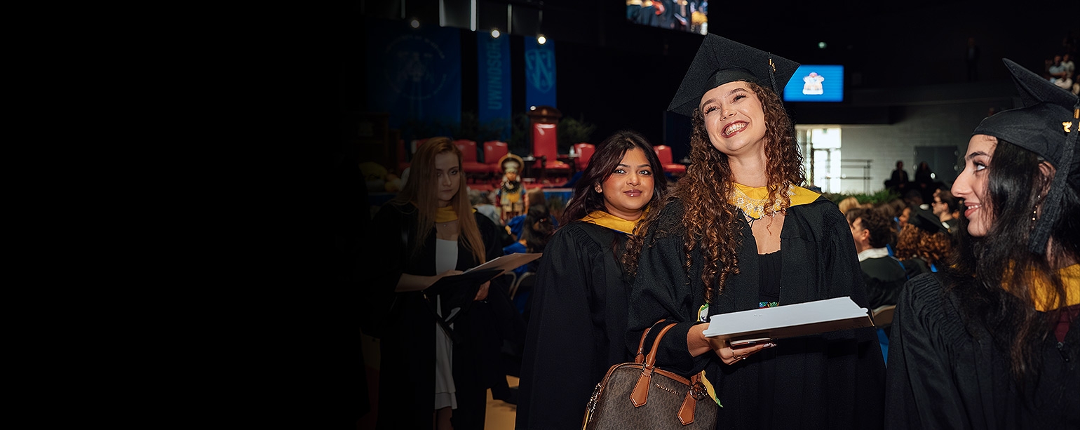 Students smiling and walking down the aisle of an auditorium
