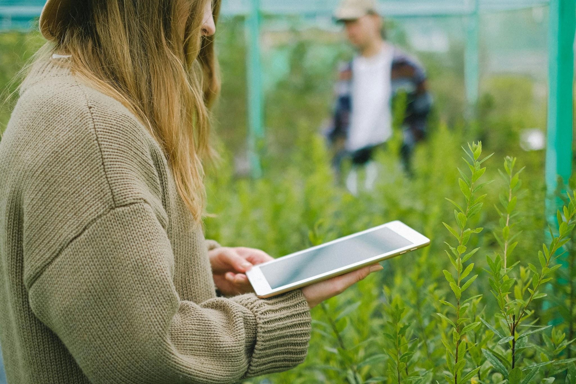 A woman holding a tablet inside a greenhouse