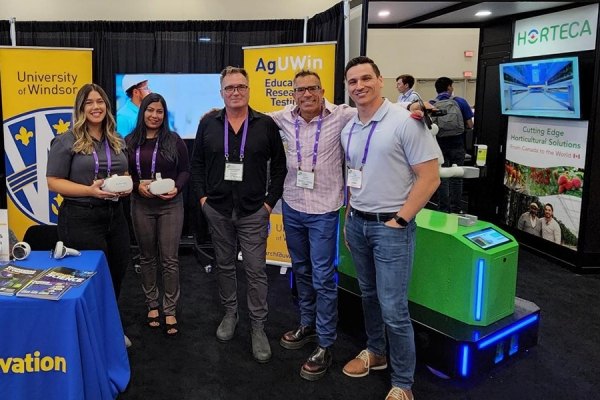 5 people standing at a AgUWin stall at a summit