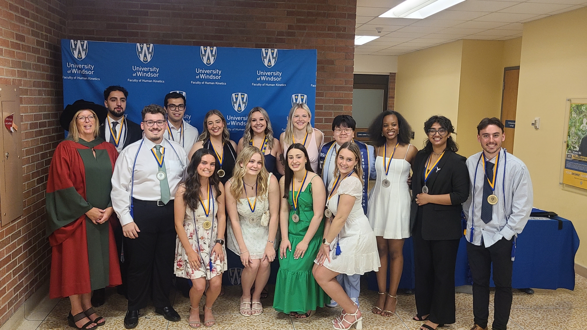 A person in a graduation cap and gown holding a medallion.