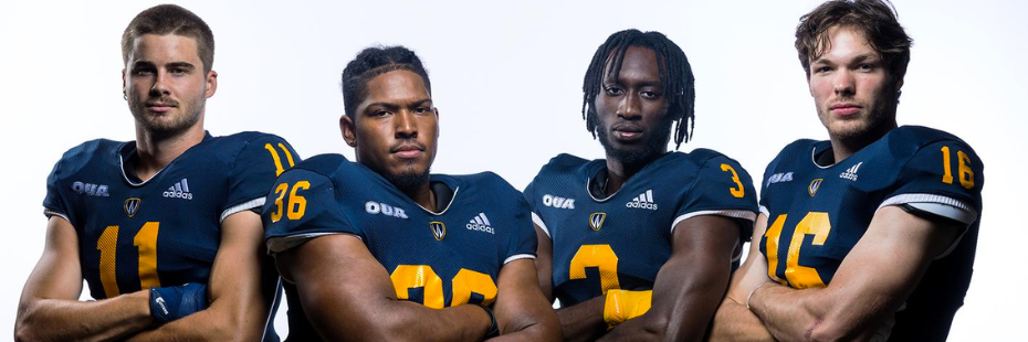 Four football players standing with their arms crossed