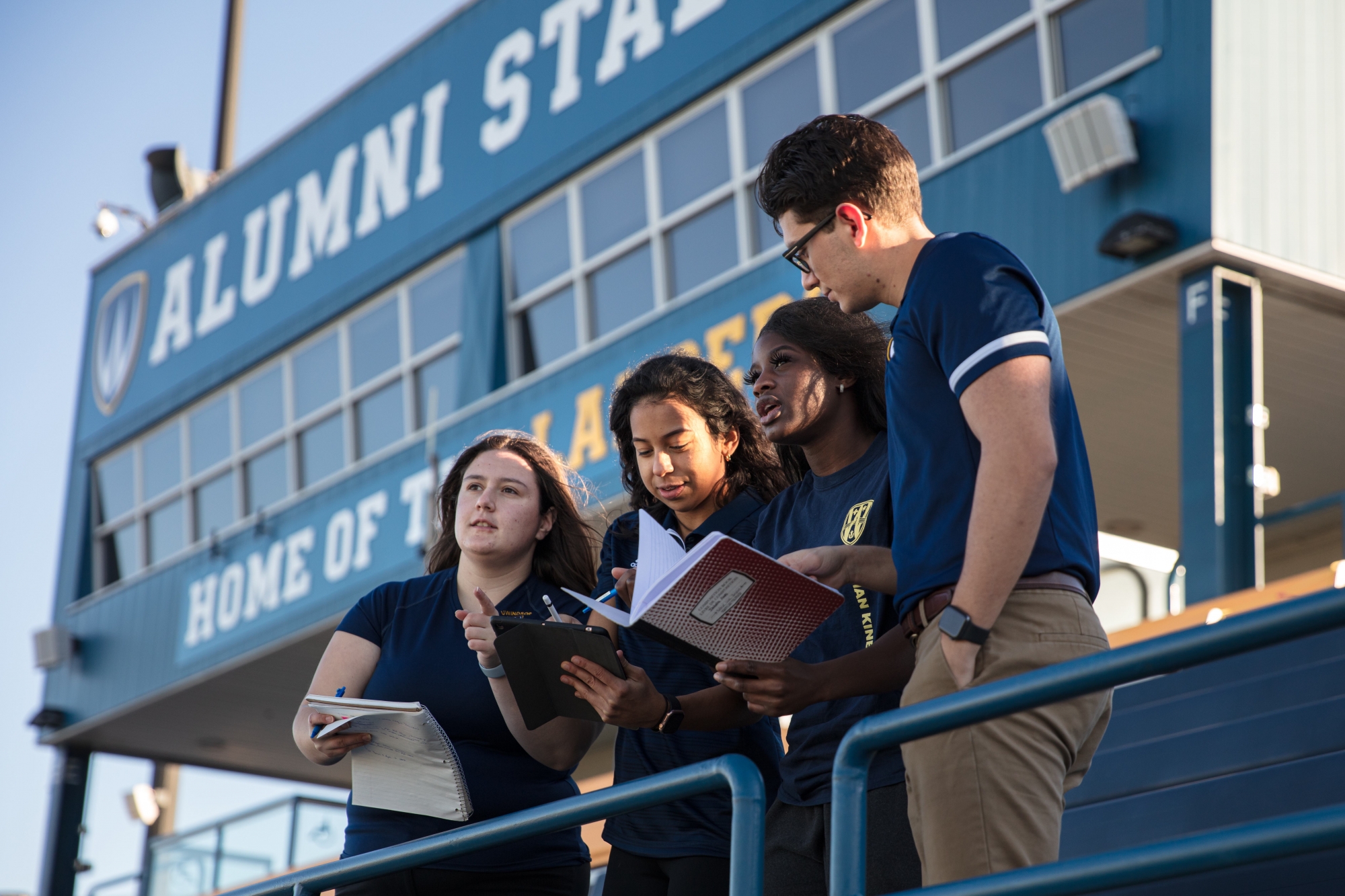 Four students overlooking a stadium field at the University of Windsor