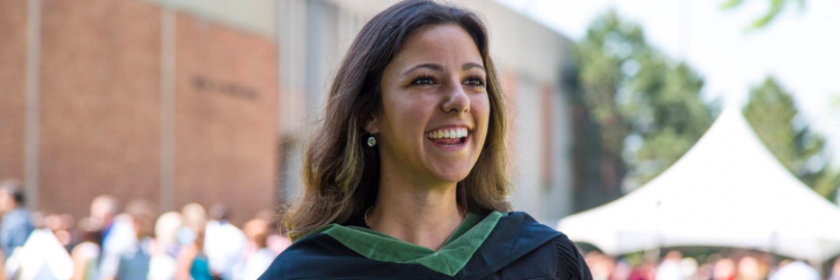 Grad wearing green faculty sash smiles