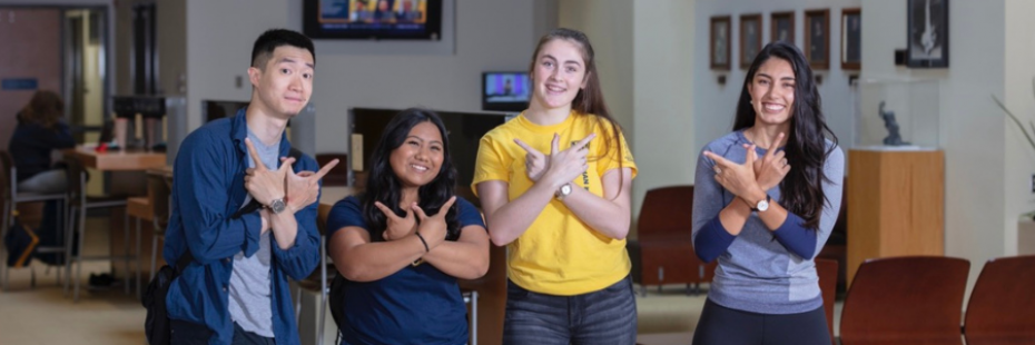 Four students using hands to make a W