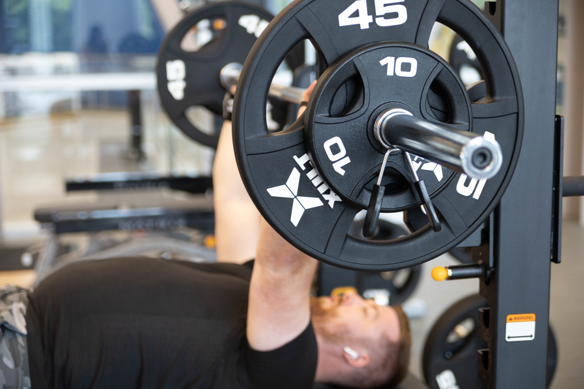 A male student lifts weights on a bench press.