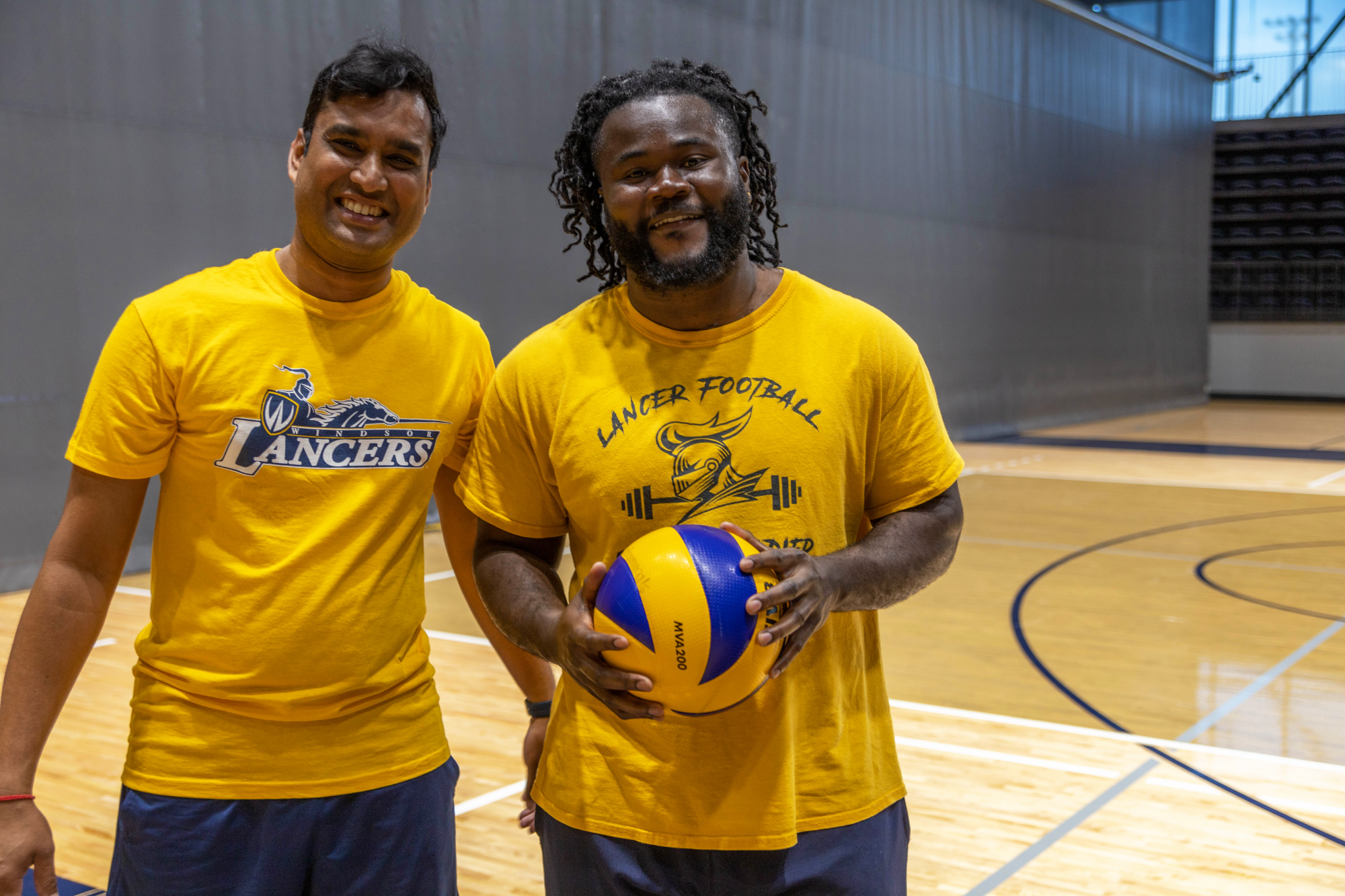 Two student smile holding a volleyball in an intramural volleyball game