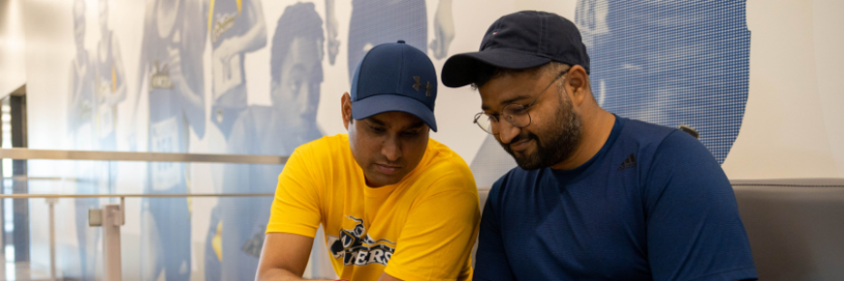 Two Uwindsor student look at a phone on a bench at Toldo Lancer Centre.