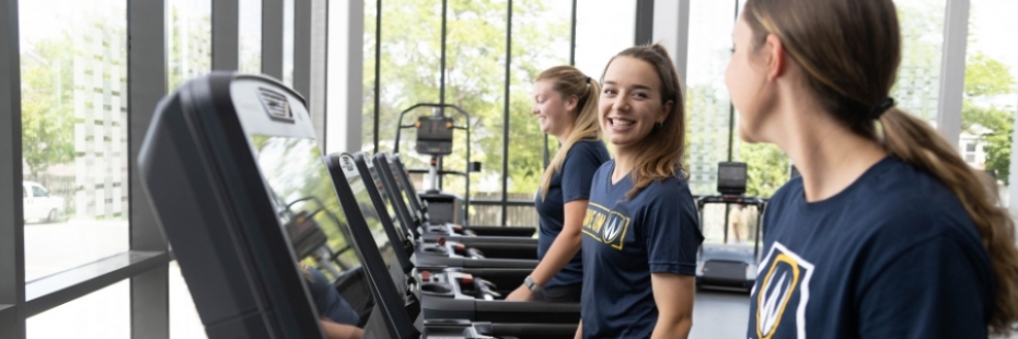 Three women walk on treadmills.