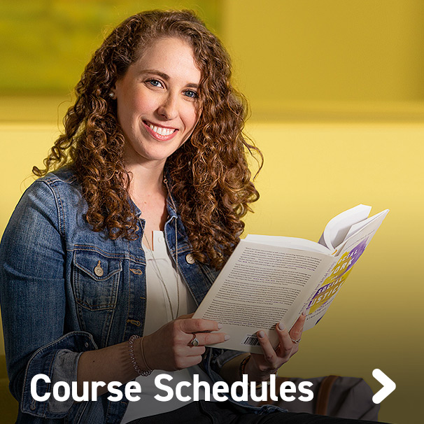 Female student with an open book smiling at camera