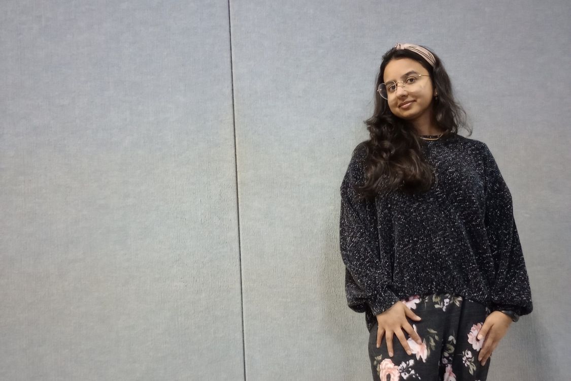 Samita Sarkar in front of a grey background wearing heart shaped glasses
