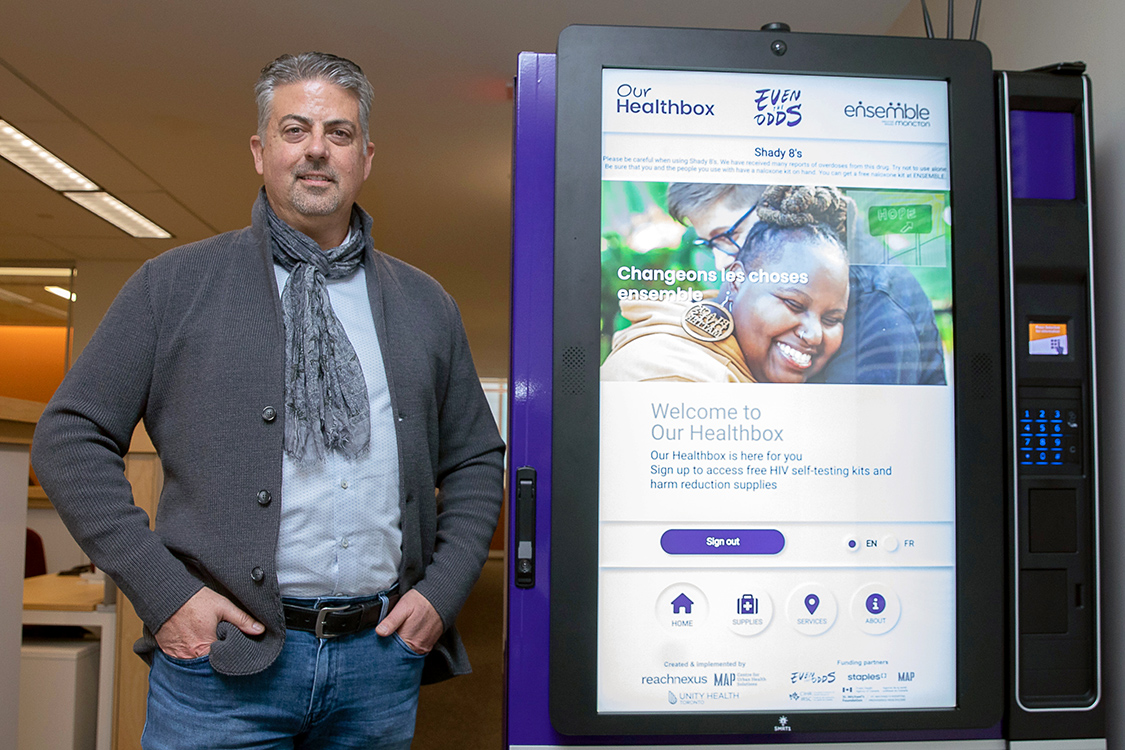 Dr. Sean Burke stands in front of an Our Healthbox vending machine
