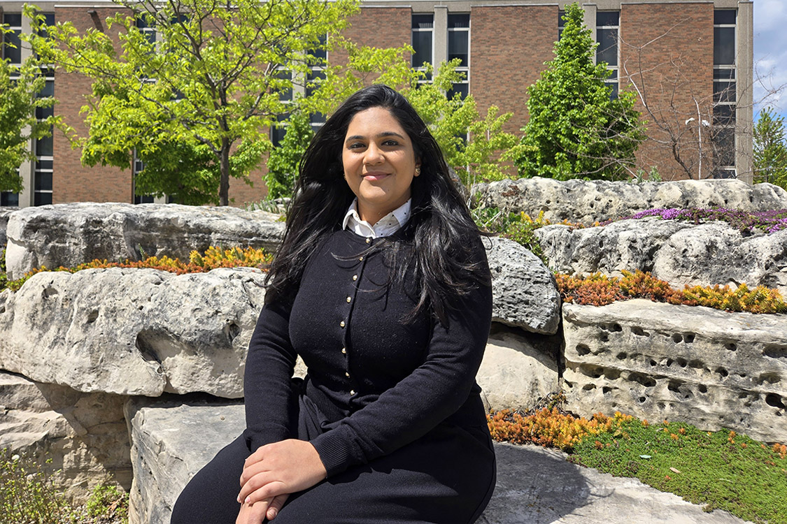 portrait of Afreen Raj Dharani sitting in landscaped area of campus