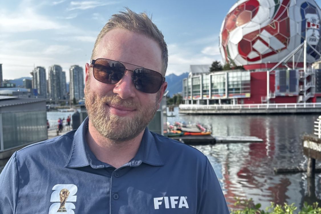 Adam Powell in a FIFA shirt in front of the Vancouver science centre dome painted like a soccer ball