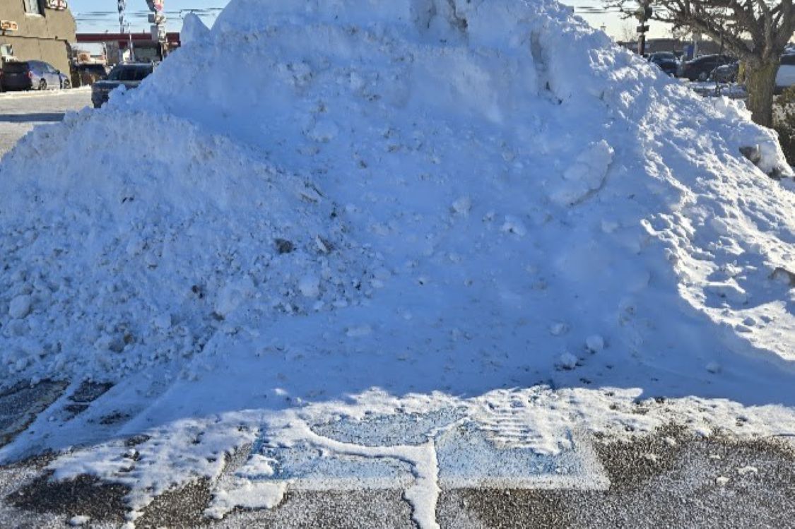 large pile of snow on an accessible parking space