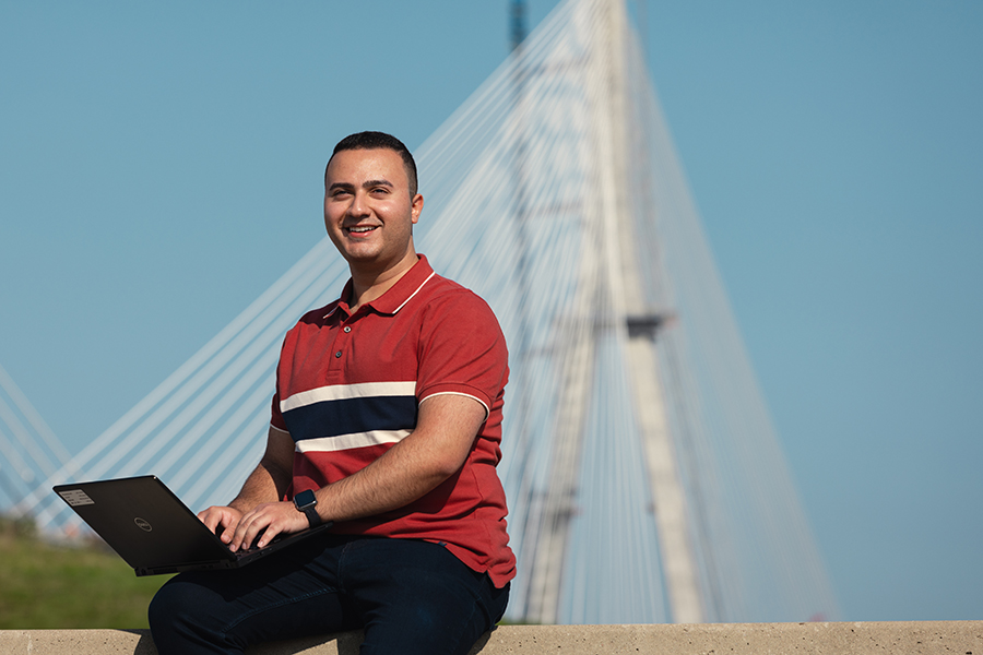 Man siting in front of bridge working on computer