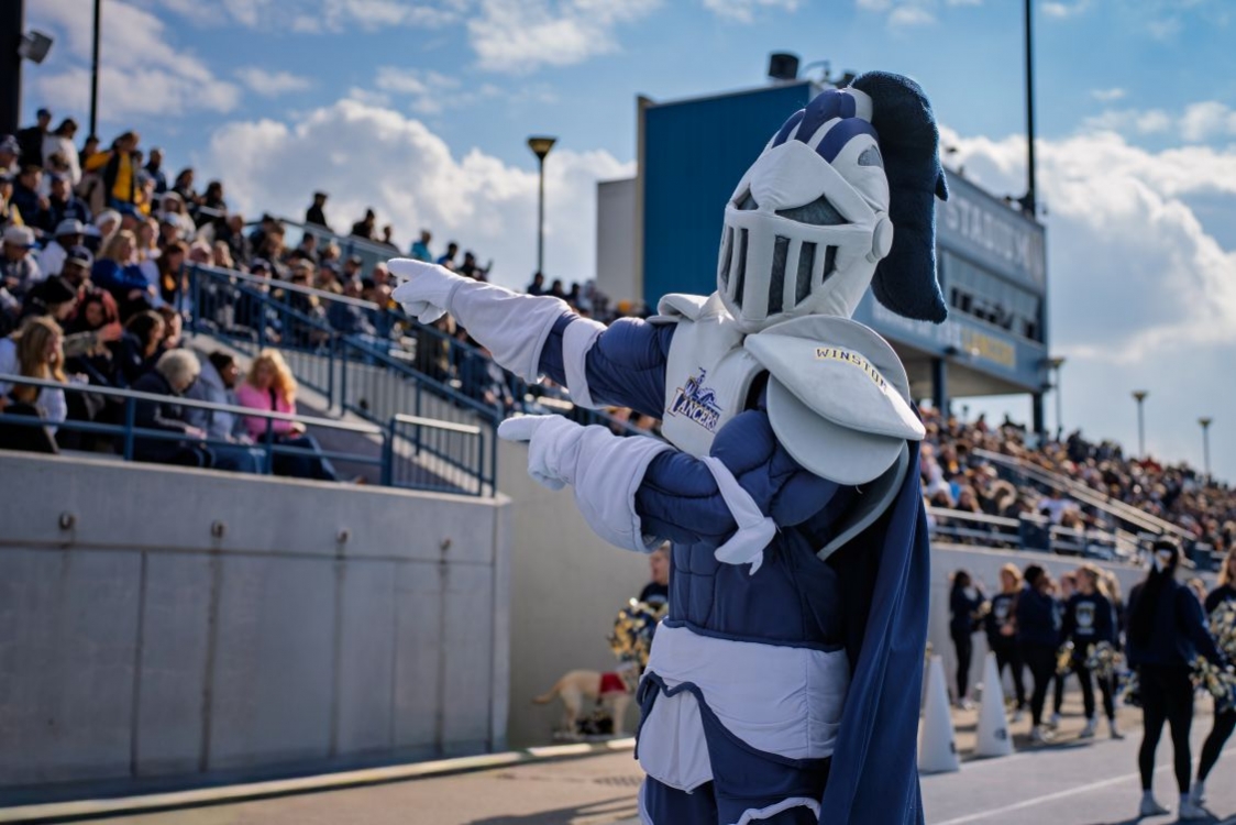UWindsor Lancer mascot Winston in front of a crowd at a football game