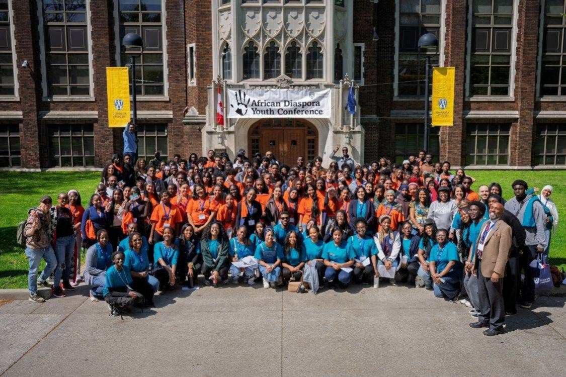 Group of students outside Dillon Hall with banner for African Diaspora Youth Conference