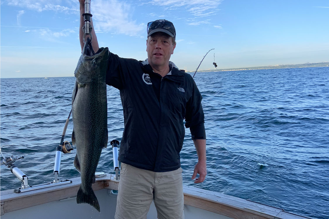 University of Windsor researcher Aaron Fisk holds a Chinook salmon caught on Lake Ontario for tagging as part of his research tracking fish movement and habitat use in the Great Lakes.