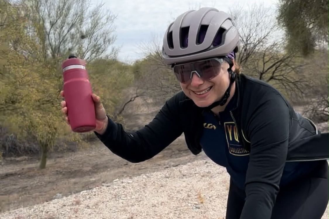 Kim Rocheleau holding a water bottle and wearing a cycling helmet