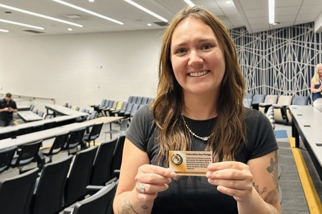 Smiling woman holding a pin on a card