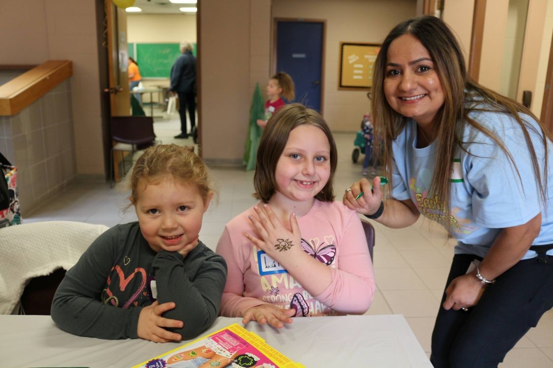A teacher candidate with two smiling children at a table