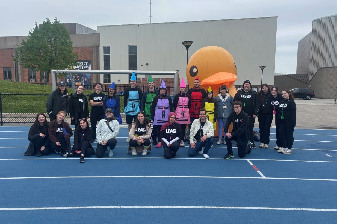 Group of teacher candidates with some dressed as crayons and a large inflatable rubber duck