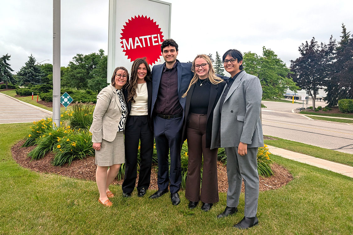 photo of MBA students standing beside Mattel Corporation sign
