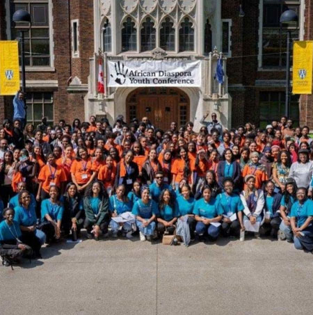 Group of students outside Dillon Hall with banner for African Diaspora Youth Conference