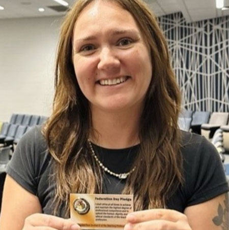 Smiling woman holding a pin on a card