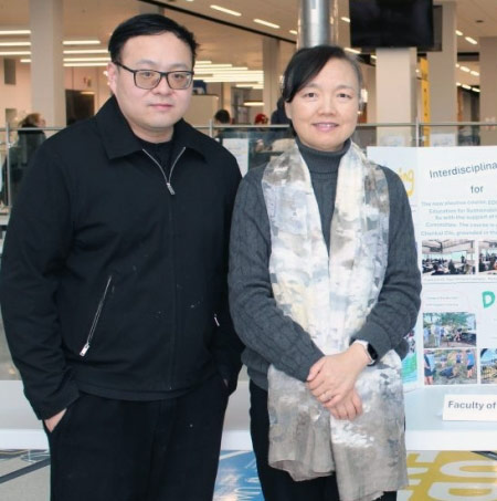 A group of people standing next to a poster board about sustainability in education