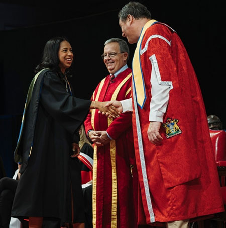 A graduating student is congratulated by Chancellor Dwight Duncan and President J.J. McMurtry