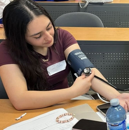 High school girl using a blood pressure cuff
