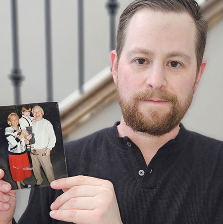 Dr. Kyle Brykman holds up a picture of his grandparents cradling him as a young boy
