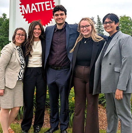 photo of MBA students standing beside Mattel Corporation sign