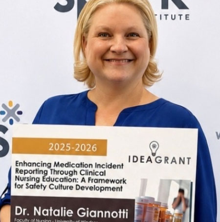 Natalie Giannotti holds a poster for her WeSpark grant project